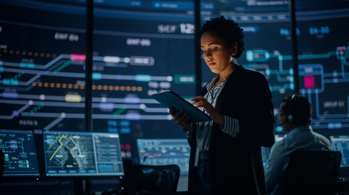 Engineer Looking at Big Screen Display Showing Global Map with Data Points